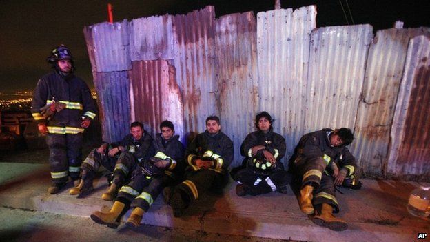 Firefighters take a break from battling blazes in the city of Valparaiso on 14 April 2014