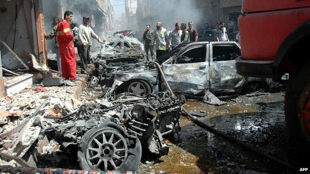 Emergency personnel and civilians inspect the site following a car bomb explosion in the Abbasiyah neighbourhood of Syria's central city of Homs, 29 April 2014