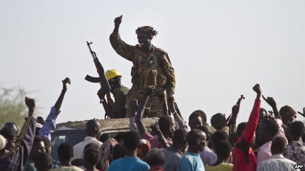 A government soldier waves his AK-47 in celebration outside the UN base in Malakal after the army said it had recaptured the town from rebels on 19 March 2014