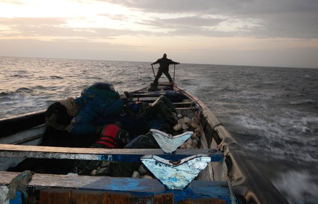 Man on prow of boat looking for fish
