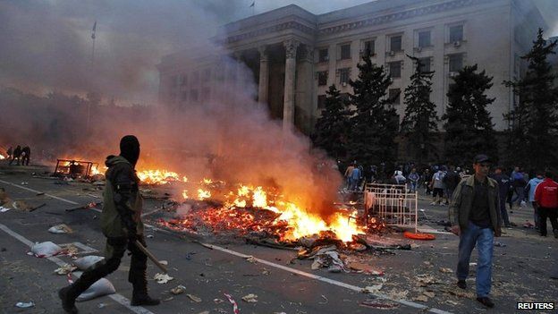 A protester walks past a burning pro-Russian tent camp near the trade union building in Odessa - 2 May 2014