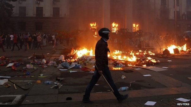 A protester walks past a burning tent camp and a fire in the trade union building in Odessa - 2 May 2014