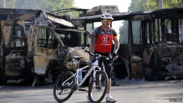 Cyclist with burned out vehicles in Kramatorsk, 3 May 2014