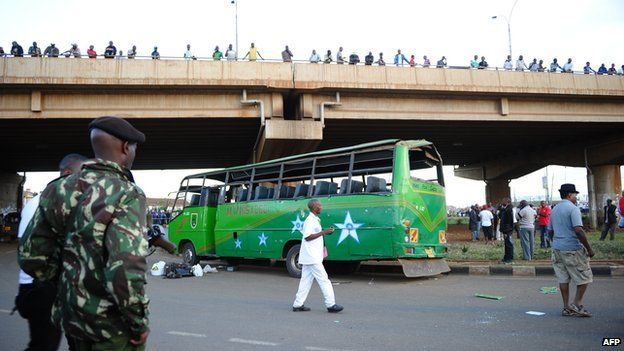 A soldier stands guard near a damaged bus after two explosions hit two buses along Nairobi's Thika road, on 4 May 2014.