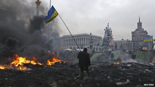 Anti-government protester carrying the national flag through Independence Square in Kiev, Feb 2014.
