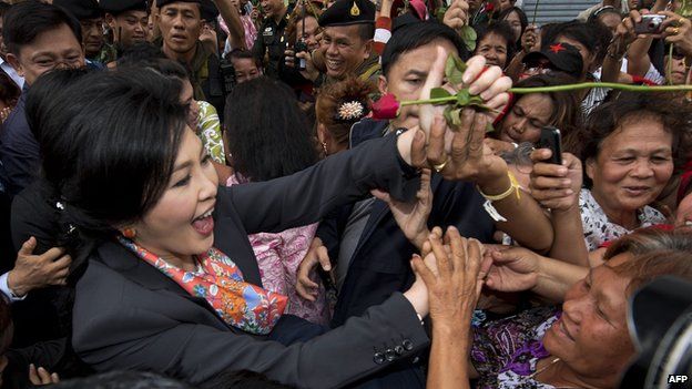 Ousted Thai Prime Minister Yingluck Shinawatra (L) receives a rose from supporters in a suburb of Bangkok on 7 May 2014.
