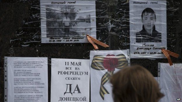 A woman reads the piece of paper reading "May 11, all on a referendum, say yes Donetsk republic" on the monument of former Soviet leader Vladimir Lenin in the centre of Sloviansk