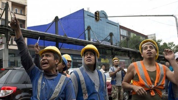 Workers look on after a strong earthquake in Mexico City on 8 May 2014.