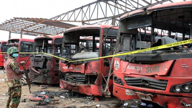 A soldier standing guard in front of burnt buses after an attack blamed on Boko Haram in Abuja, Nigeria - 14 April 2014