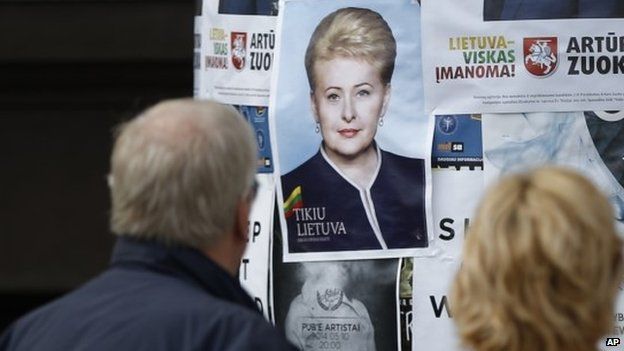 People look at an election poster of Dalia Grybauskaite in Vilnius