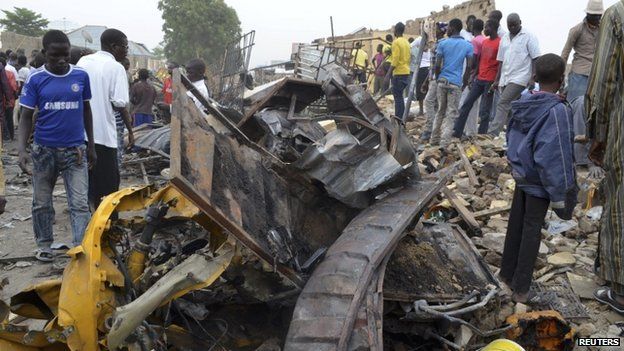 People look at damage in a market area after a bomb explosion in Ajilari-Gomari near Maiduguri's airport, Borno State, 2 March 2014