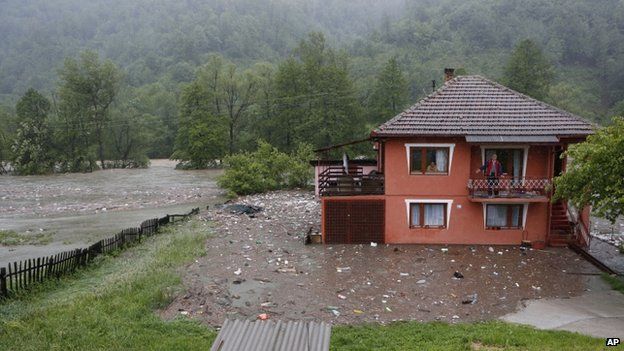 A Bosnian man looks out from a balcony at floodwaters surrounding his house in the village of Topcic Polje, near the central Bosnian town of Zenica, on 15 May 2014.