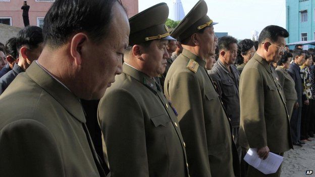 North Korean officials stand among the families of victims