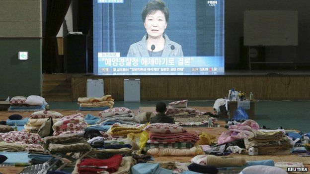 A relative of missing passengers onboard sunken ferry Sewol watches a broadcast of South Korea's President Park Geun-hye speech to the nation, at a makeshift accommodation at a gymnasium in Jindo, 19 May.