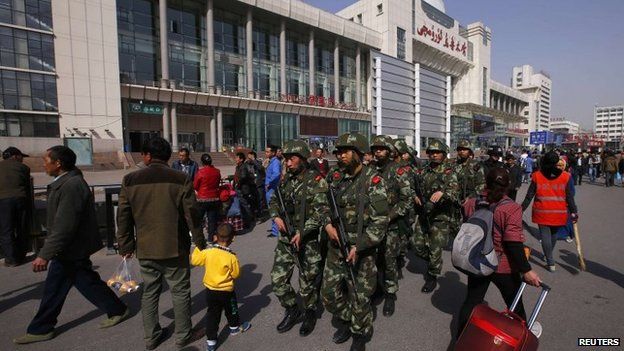 Armed policemen patrol near the exit of the South Railway Station in Urumqi on 2 May 2014