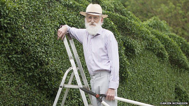 John Brooker standing with hedge clippers on a stepladder