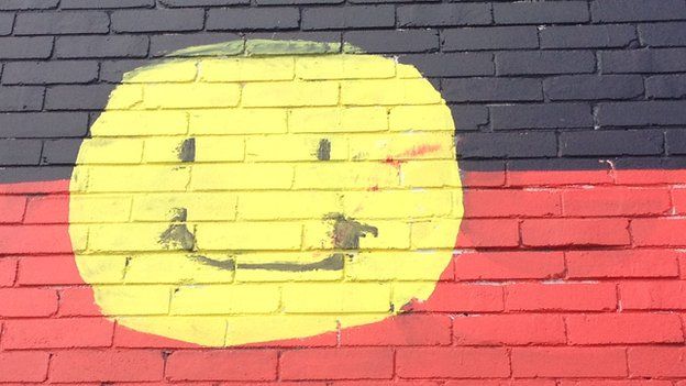 A smiley face painted onto the Aboriginal flag