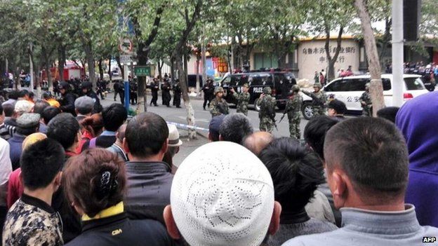 Residents gather to watch as police seal off the site where attackers ploughed two vehicles into a market and threw explosives, killing at least 31 people, in Urumqi in northwest China's Xinjiang region on 22 May 2014