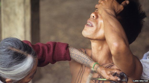 Whang-Od tattooing a client