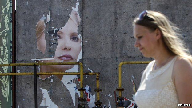 A woman and her daughter walk past a torn poster of Ukrainian politician and presidential candidate Yulia Tymoshenko in Luhansk, eastern Ukraine, May 16