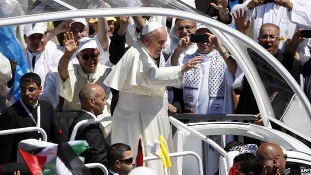 Pope Francis waves to the crowd, from his popemobile, as he arrives at the Manger Square