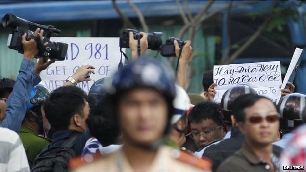 Police and security personnel film protesters holding placards which read, "Haiyang 981 oil rig get out of Vietnam (L)" and "Take China to the international court" (R) as they march during an anti-China protest in Vietnam's southern Ho Chi Minh city May 18, 2014. Vietnam flooded major cities with police to avert anti-China protests on Sunday in the wake of rare and deadly rioting in industrial parks that deepened a tense standoff with Beijing over sovereignty in the South China Sea. Several arrests were made in the capital Hanoi and commercial hub Ho Chi Minh City within minutes of groups trying to start protests, according to witnesses, as Vietnam's communist rulers stuck to their vow to thwart any repeat of last week's violence in three provinces in the south and centre