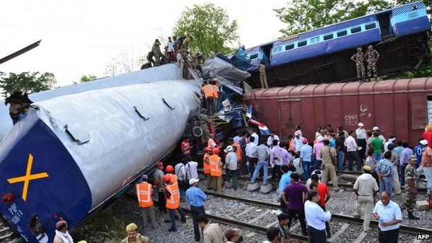 Indian officials and rescuers stand near the wreckage after the Gorakhpur Express passenger train slammed into a parked freight train at Chureb in Uttar Pradesh state, Monday, May 26, 2014.