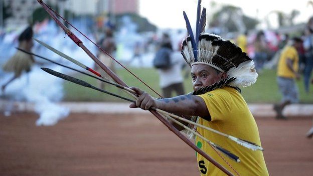 An indigenous Brazilian protesters aims an arrow at riot police who fired tear gas at demonstrators in Brasilia - 27 May 2014