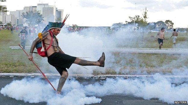 A native Brazilian kicks a tear gas grenade back at riot police in Brasilia - 27 May 2014