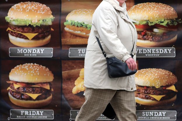 Woman walking past burger shop