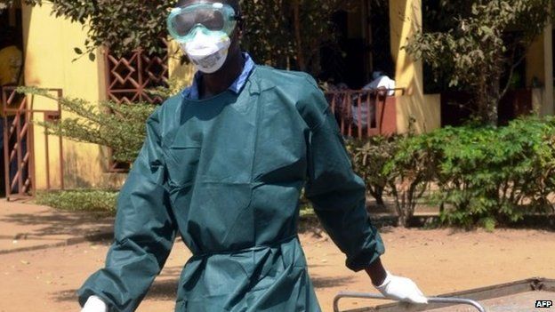 A health worker in light protective gear walks on 31 March 2014 in the yard of the isolation ward of the Donka hospital in Conakry, Guinea