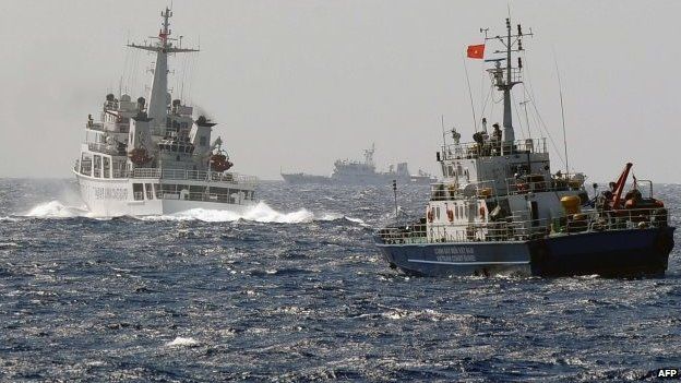 File photo: A China Coast Guard ship (left) blocks the way of a Vietnam Coast Guard ship near to the site of a Chinese drilling oil rig (right, background) being installed at the disputed water in the South China Sea, 14 May 2014