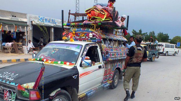 Pakistani soldier inspects truck loaded with belongings