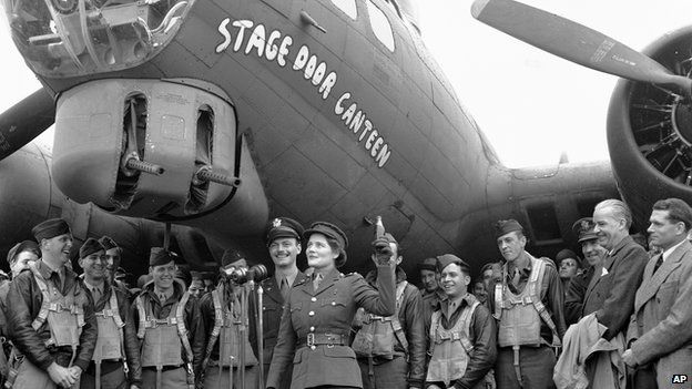 Subaltern Mary Churchill christens the new Flying Fortress, 'Stage Door Canteen', by breaking a bottle of Coca-Cola across the nose, April 23, 1944, in England. Laurence Olivier is standing at far right.