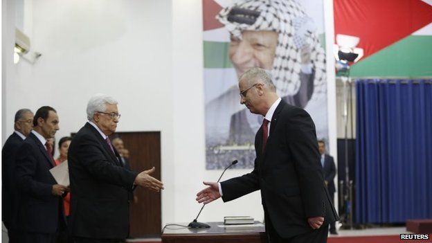 Palestinian President Mahmoud Abbas shakes hands with Rami Hamdallah at swearing-in ceremony in Ramallah (02/06/14)
