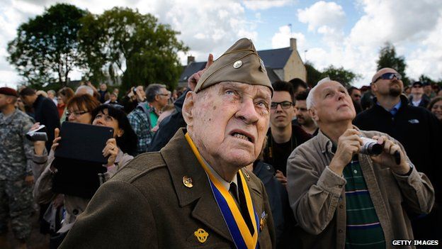 Veteran Raymond W. Sylvester, 95, watches as paratroop veterans drop into Picauville