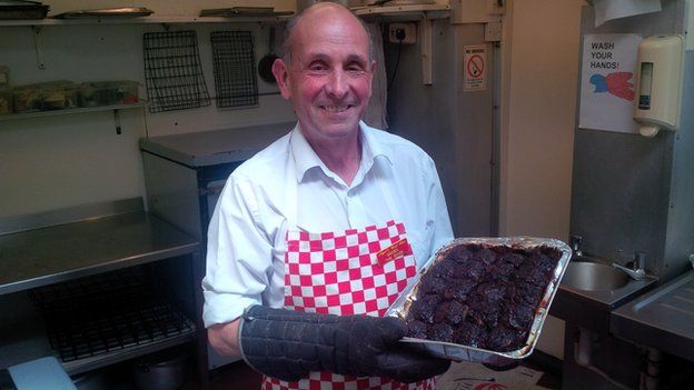 The Cook Shop's owner Nigel Brazier holding a tray of faggots