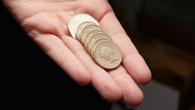 A hand holding coins totalling £6.50, the new minimum wage from October