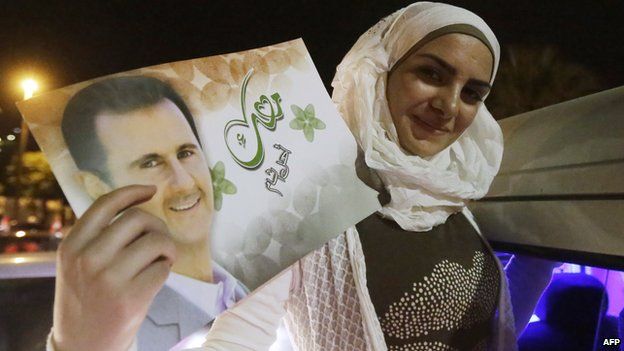 A woman holds a picture of re-elected Syrian President Bashar al-Assad as she celebrates in Damascus after he was announced as the winner of the country"s presidential elections on June 4