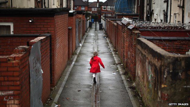 Child runs through back lane behind houses