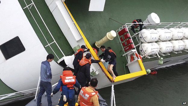 In this file photo taken on 16 April, 2014, South Korean coast guard officers rescue ferry Sewol captain Lee Joon-seok, wearing a sweater and underwear, from the ferry in the water off the southern coast near Jindo, South Korea
