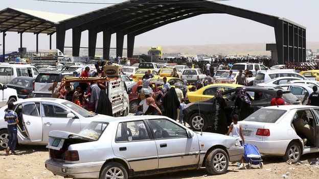 Families fleeing the violence in the Iraqi city of Mosul arrive at a checkpoint in outskirts of Irbil, in Iraq's Kurdistan region, on 10 June 2014