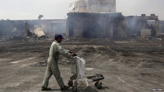 A man pushes a trolley past a damaged building on the tarmac of Jinnah International Airport, a day after Sunday's attack by Taliban militants, in Karachi, 10 June 2014