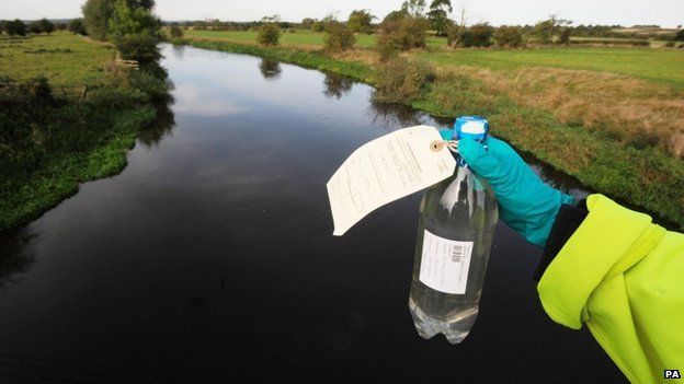 An Environment Agency worker holds a sample bottle of water from the River Trent at the time of the leak