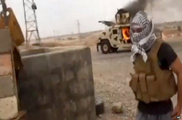 An Islamist fighter near a burning Iraqi army Humvee in Tikrit, 12 June