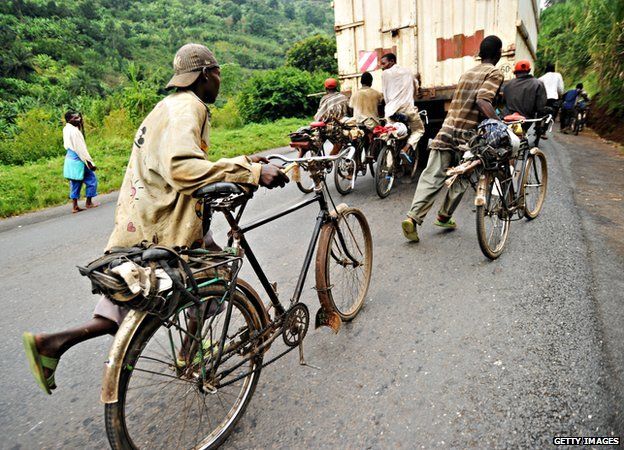 Burundian bicycle transporters run in Bujumbura to reach the back of a truck to hold onto to take an almost effortless ride up the mountain