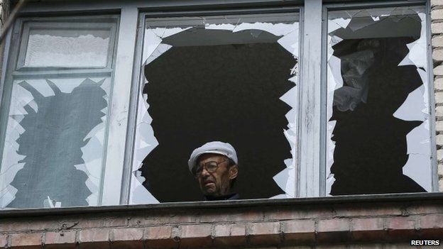 A man looks out of the broken window of his home in a residential building which was damaged by what locals say was overnight shelling by Ukrainian forces in the eastern town of Slaviansk