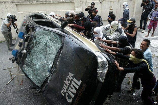 Demonstrators push over a police car during a protest in Belo Horizonte, Brazil - 12 June, 2014