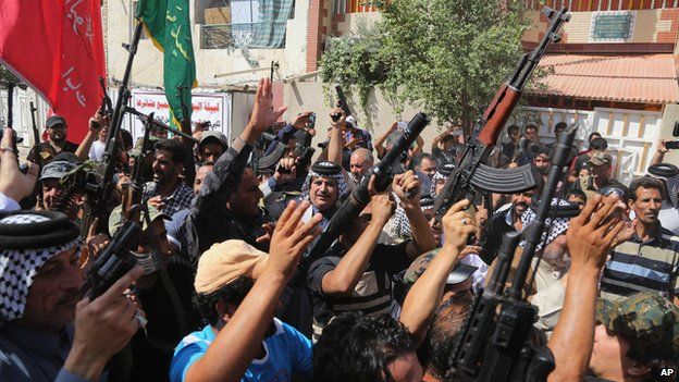 Iraqi Shiite tribal fighters raise their weapons in Baghdad's Sadr City,