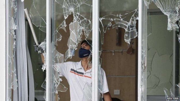 A man clears broken windows at the office of a Taiwanese company attacked in anti-China protests in Vietnam